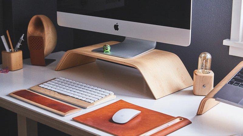 "Modern minimalist workspace setup featuring an Apple iMac on a wooden stand, wireless keyboard, and stylish desk accessories. Perfect for productivity and aesthetics."